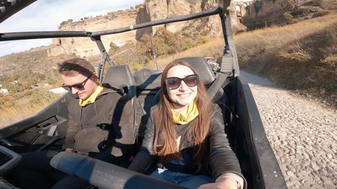 Young couple driving a buggy UTV ATV Can-am polaris on desert off-road in Ronda, Spain, on a sunny day . Couple having fun riding a ATV off-road.