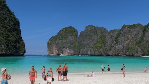 Maya Bay beach panning view over rocky cliffs, beautiful coastline and tourists taking photos, selfies. Excellent travel destination for trips. Krabi, THAILAND - January 3 , 2022
