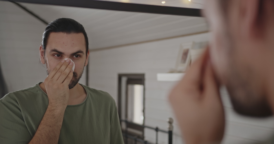 Portrait of a man reflection in the mirror cleansing the skin of the face.