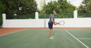Video of biracial senior man holding racket and starting match on tennis court. active retirement lifestyle, senior relationship and tennis training concept.