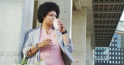 Plus size biracial woman drinking coffee in city. digital nomad on the go, body inclusivity.