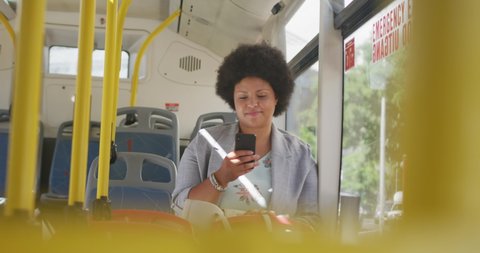 Happy plus size biracial woman using smartphone in bus. digital nomad on the go, body inclusivity.