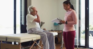 Video of biracial female physiotherapist examining caucasian senior man. seniors health and nursing home lifestyle concept digitally generated video.