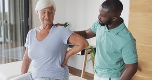 Video of caucasian senior woman practicing with african american male physiotherapist. seniors health and nursing home lifestyle concept digitally generated video.