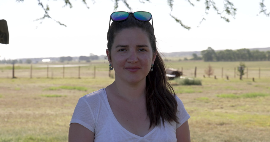 A woman with glasses on her head looks at the camera smiling, in a natural environment.
Concept of well-being, happiness, pleasure, happiness, sympathy, power of women. | Shutterstock HD Video #1090425255
