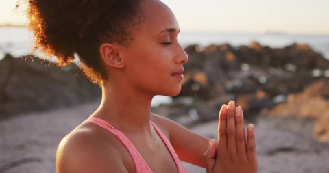 Close up view of african american woman practicing yoga and meditating on the rocks near the sea. healthy lifestyle concept
