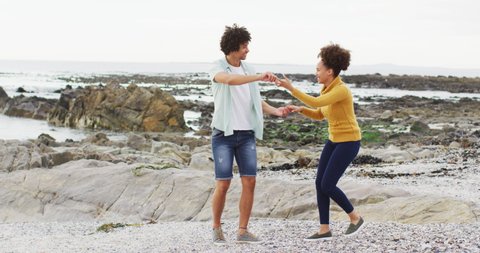 African american couple dancing together on the rocks near the sea. love and relationship concept