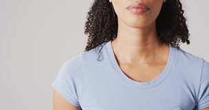 Video of biracial woman touching her neck on white background. global medicine and healthcare concept.