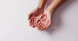 Video of hands of caucasian woman holding violet and pink ribbons on white background. medicine, health, cancer awareness concept digitally generated video.