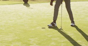 Video of legs of african american man playing golf on golf field. sporty, active lifestyle and playing golf concept.