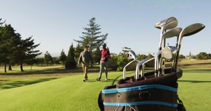 Video of diverse male friends walking on golf field. sporty, active lifestyle and playing golf concept.