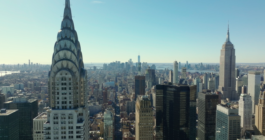 Forwards fly around Chrysler Buildings decorative top section. Cityscape in backlit. Manhattan, New York City, USA in 2021