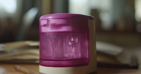 Pencil is inserted into an electric pencil sharpener, which automatically starts sharpening