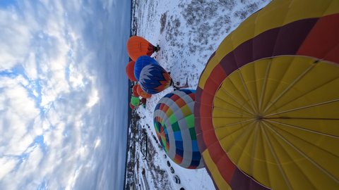 Vertical FPV 4k Aerial View of Colorful Hot Air Balloons Parachutes on Cold Winter Day Preparing to Take Off, Dynamic Drone Shot