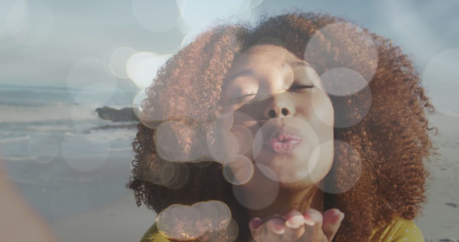 Animation of bokeh over happy biracial woman sending kisses. love, romantic relationship and valentines day concept digitally generated video. | Shutterstock HD Video #1090432371