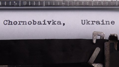 Typing name of village in the Kherson region of Ukraine "Chornobaivka, Ukraine" on retro typewriter.