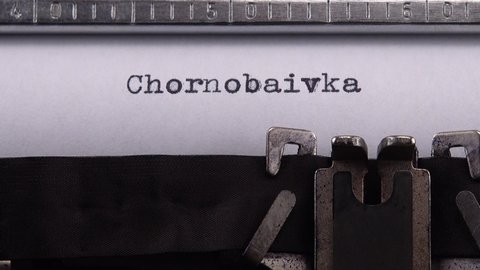 Typing name of village in the Kherson region of Ukraine "Chornobaivka" on retro typewriter.