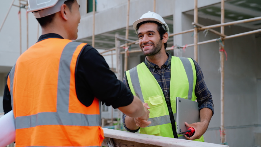 Slow motion view of professional male civil engineers workers shaking hands together supporting encouraging and cooperating team working at construction building, Cooperation with team concept