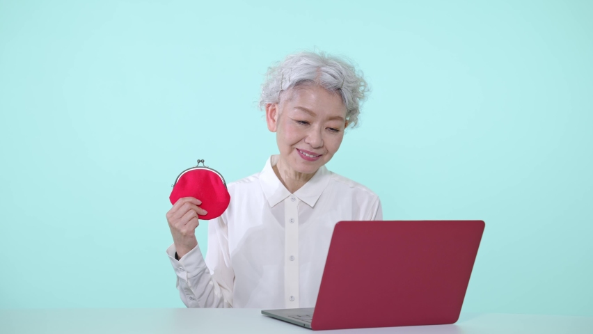 Asian senior woman who uses a laptop PC with a wallet. | Shutterstock HD Video #1090438803