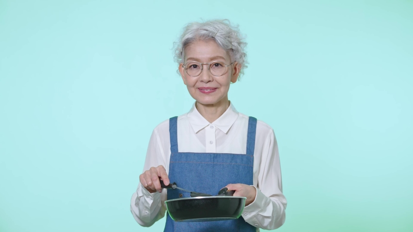 Cooking Asian senior woman with an apron. | Shutterstock HD Video #1090438841