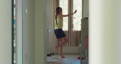 Cinematic authentic shot of carefree teen girl is having fun to dance alone behind mirror in her nursery.