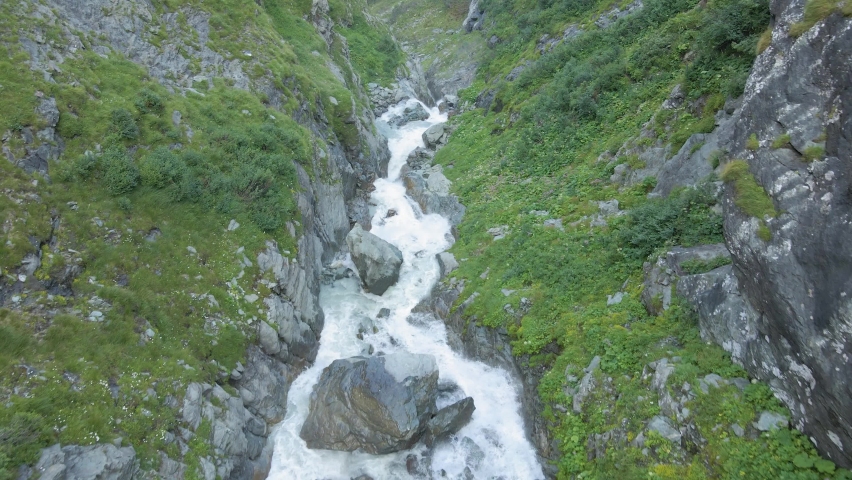An aerial slow movement around flowing river between greenery mountains | Shutterstock HD Video #1090439967