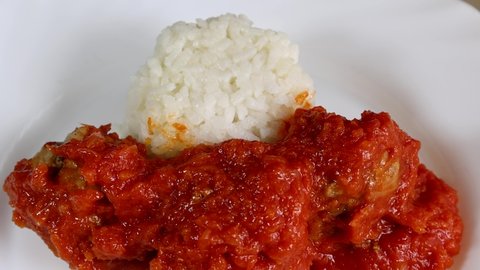 Serving a dish of rice and meatballs with tomato on a plate for lunch