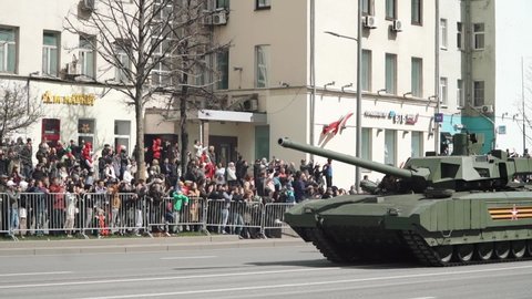 MOSCOW, RUSSIA - May 9, 2022: T-14 Russian main battle tank with an uninhabited turret, based on the Armata universal tracked platform. Spectators and military equipment traveling from the parade
