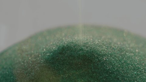 Close-up of the crumbling green sand of the sand clock. Selective focus
