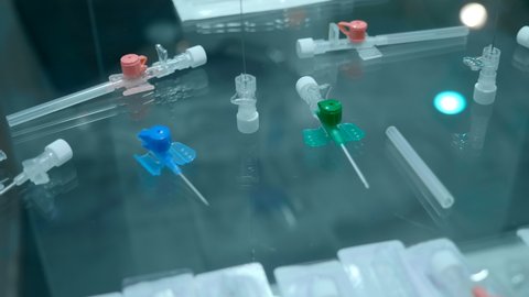 New samples of medical peripheral intravenous catheters of various sizes and purposes on a glass shelf at the exhibition of medical innovations. Closeup. Shot in motion