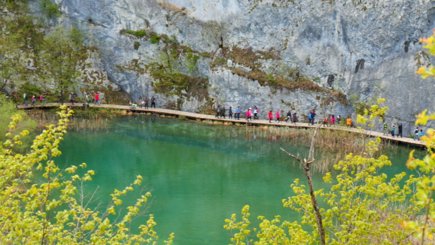 Plitvice Lakes National Park in 4K. Tourists strolling along the wooden path between the turquoise-colored lakes at the Plitvice Lakes National Park, Croatia. UNESCO world