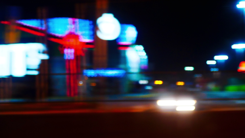 Blurred view of the night city from the car window. Beautiful moving background with bright colorful lights. Evening streets, illuminated highways, advertising signs, shopping centers and gas stations Royalty-Free Stock Footage #1090443741