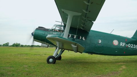 Russia. Tanay 25 August 2021: Light-engine Green Airplane begins to move across the Field. Gaining Speed for Takeoff. Camera Follows Parallel to Aircraft. Rural Airfield with Grass Runway. Takeoff