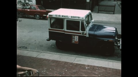 1970s: City neighborhood, mail truck pulls up to curb, man waves. Woman stands on stoop, waves, smiles. Men remove mail bags from truck, carry to stoop.