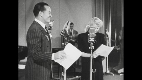 1940s: Lana Turner and Bob Hope perform comedy routine on sound stage; armed military guard escort steak onto stage.