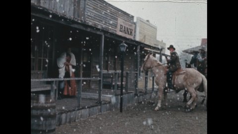 1880s: snow outside wild west bank. Sheriff with shotgun in street. Man on horse with gun. Men leave town on horseback. Men on horses in mountains. Man arrives on horse at night.