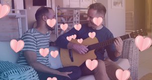 Animation of hearts over diverse male couple playing guitar. valentines day and celebration concept digitally generated video.
