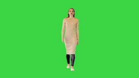 Robotic girl in beige dress walks looking straght ahead on a Green Screen, Chroma Key.