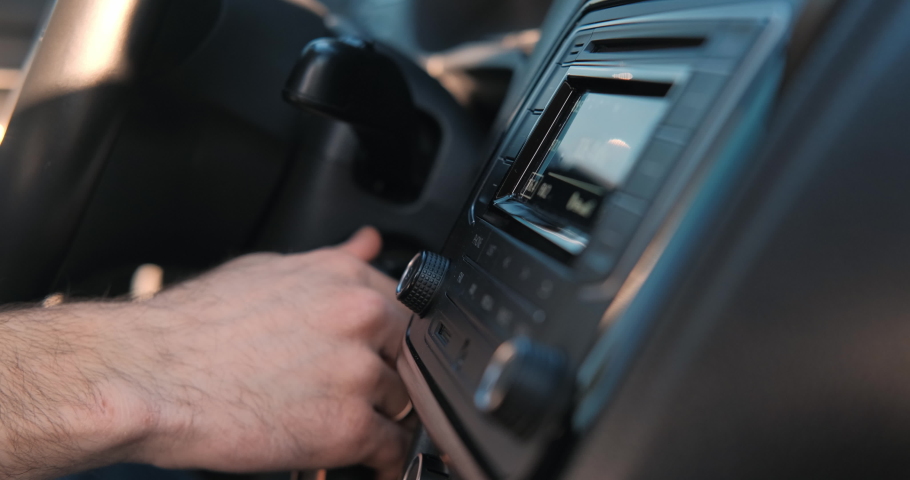 The guy turns up the volume of the music in the car. Close-up