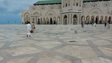 Casablanca, Morocco - 06.18.2021: Moroccan people walking to The beautiful Hassan 2 mosque built over the Atlantic ocean in Casablanca city at the obligatory prayer time.