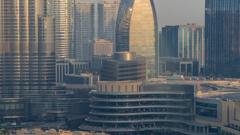Shopping mall exterior with reataurants near fountain in Dubai downtown aerial timelapse, United Arab Emirates. Bridge over lake and walking area early morning during sunrise