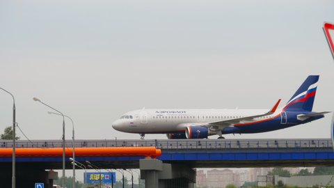 MOSCOW, RUSSIAN FEDERATION - JULY 28, 2021: Side view, Airbus A320 of Aeroflot taxiing over the highway at Sheremetyevo airport. Car traffic in the foreground