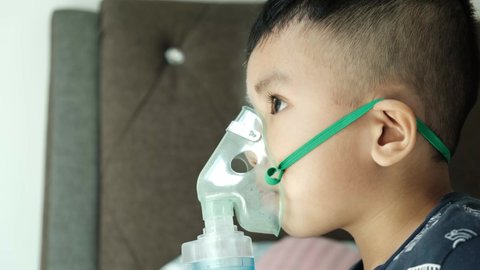 A handheld close up footage of a boy using home nebulizer machine for treating asthma, bronchitis and illness related to respiratory