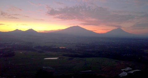 View of Merapi volcano and mounts Merbabu, Andong and Telemoyo during a colorful pink and orange sunrise