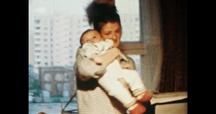 Young mother with baby in Soviet apartment interior room. Happy mom playing with small child. Women's love for child. Cinema vintage color film. Retro 80s, 90s. Family home archive 8mm. 1980s-1990s 