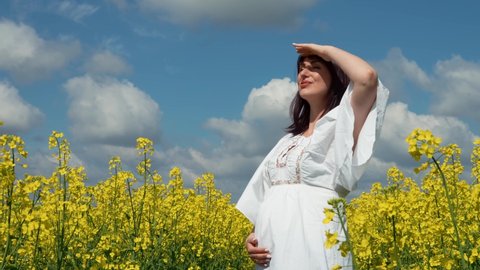 Ukraine, Lviv region, Ukrainian pregnant woman among rapeseed field enjoys nature and freedom