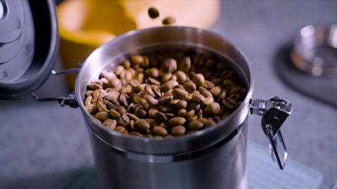 Footage of man hand scooping coffee bean from an air tight container. A person preparing an espresso drinks 