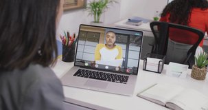 Video of caucasian woman having video call on laptop with biracial female coworker. business, cooperation and working in office with technology concept digitally generated video.