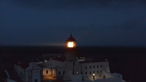 Amazing aerial view of historic Lighthouse in Lagos Algarve, Portugal, circle pan dolly out reveal breathtaking sea landscape, evening dusk