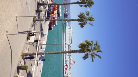 Malaga, SPAIN - April 21 2022:  Vertical video of the port of Malaga. View of the promenade area of the harbour. The Transmediterranean ferry docked in the port. People taking cruise ships.